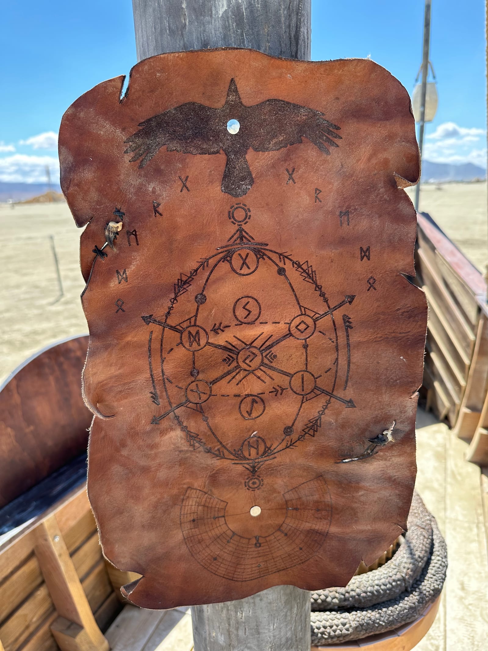 A tooled leather panel hung on the mast, burned with a raven above a rune compass and a ring of staves