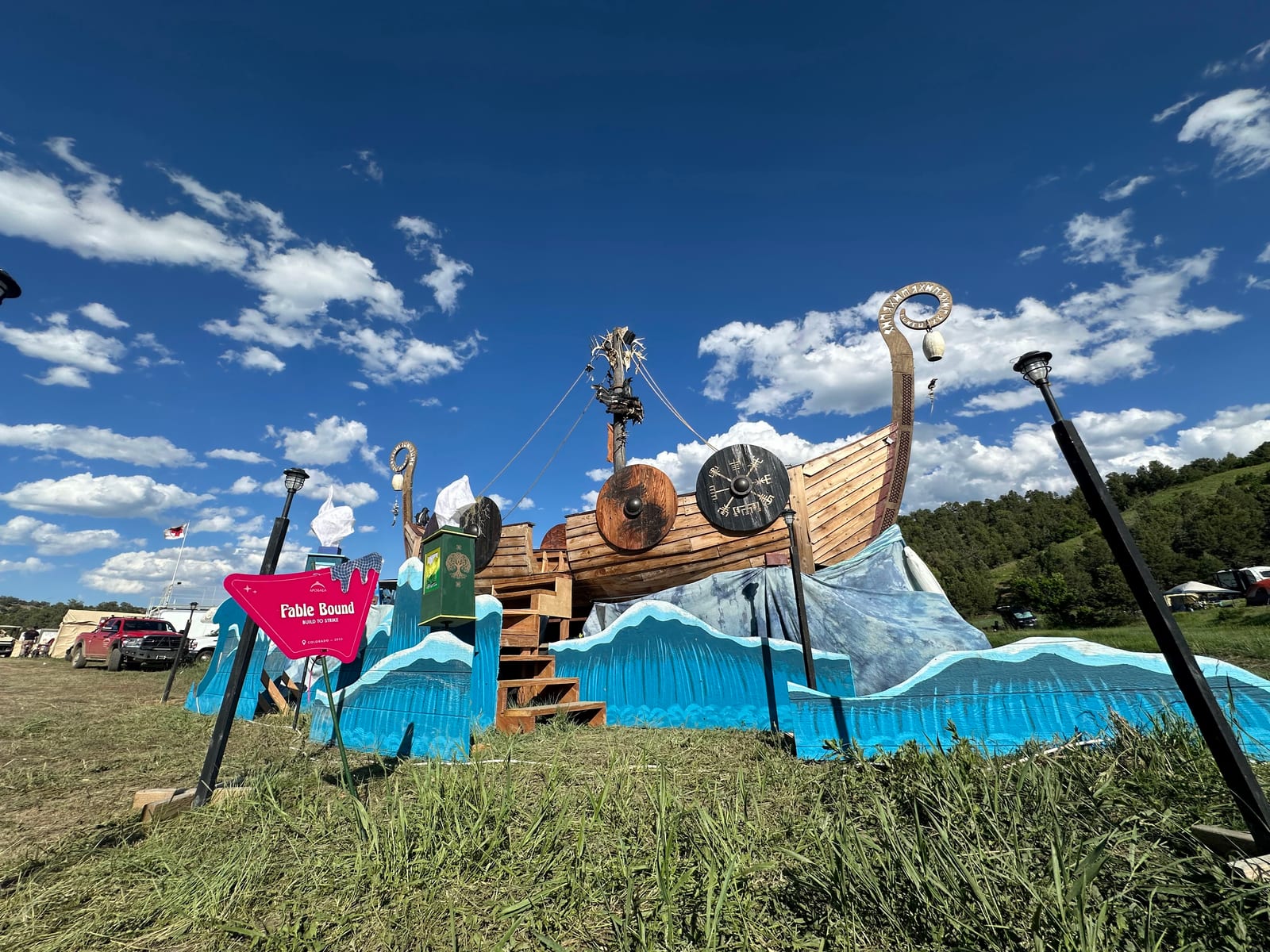 The ship broadside on a grass field under a bright blue sky, its Fable Bound sign staked in the foreground
